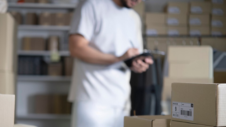 retail store employee entering data into a device in the stock room of the store
