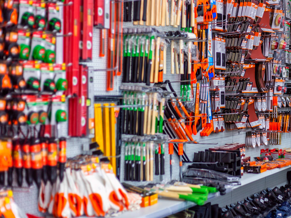 multi-colored household workshop tools hanging on wall display in retail diy hardware store