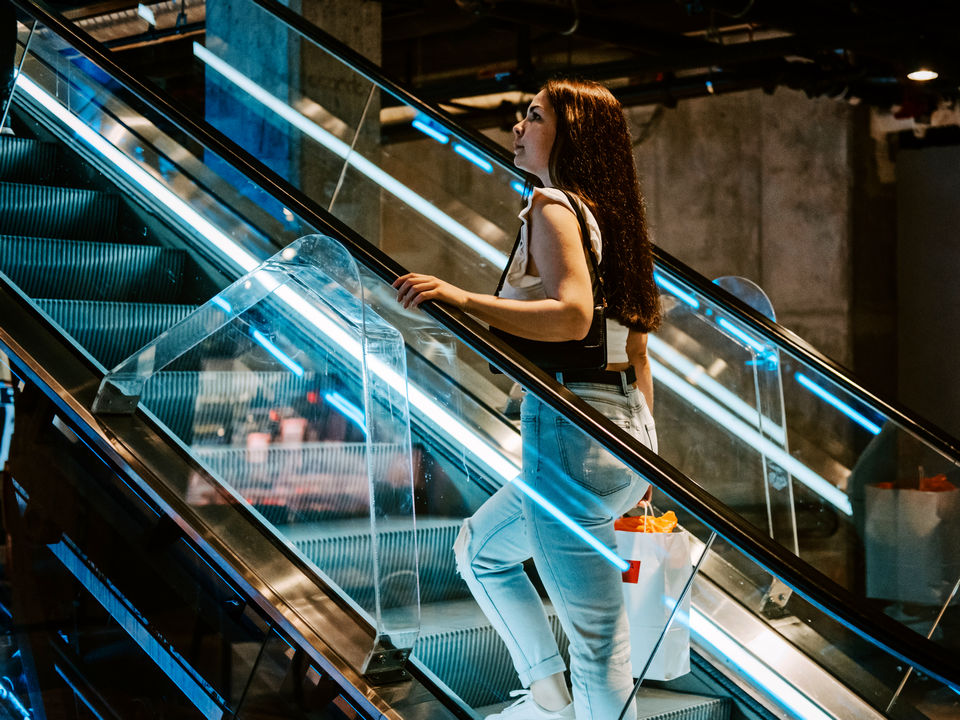 woman shopper riding up escalator in a multi-level retail shopping mall