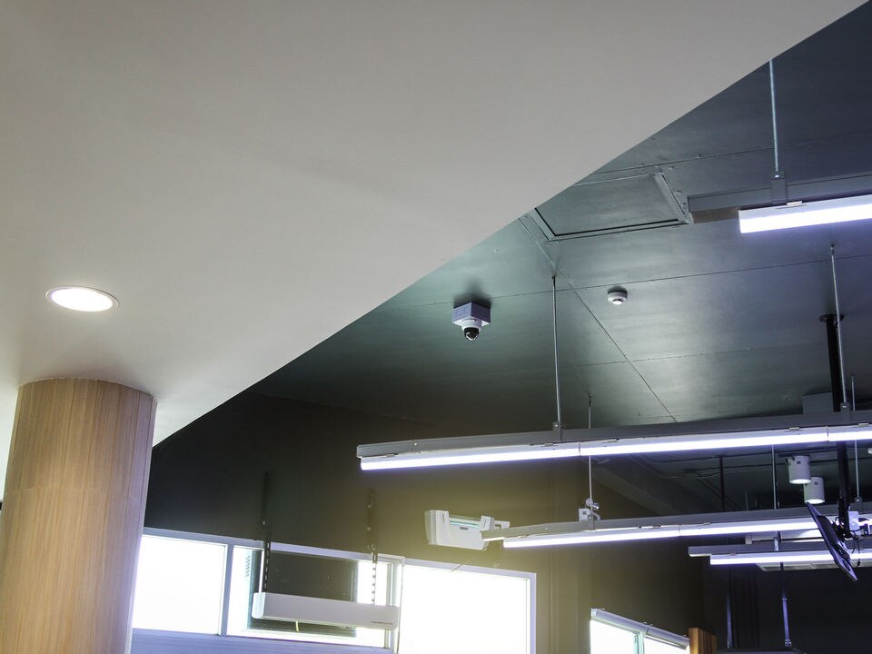 retail store ceiling with fluorescent lights power lines and ip video surveillance camera