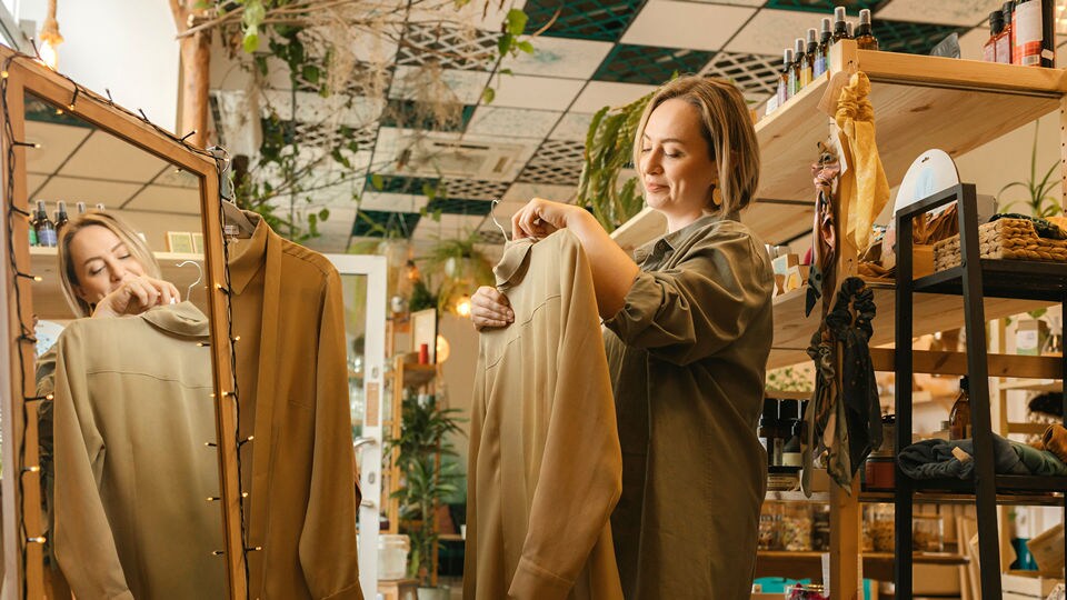 female shopper considering a purchase of a light jacker in an upscale boutique retail womens apparel store