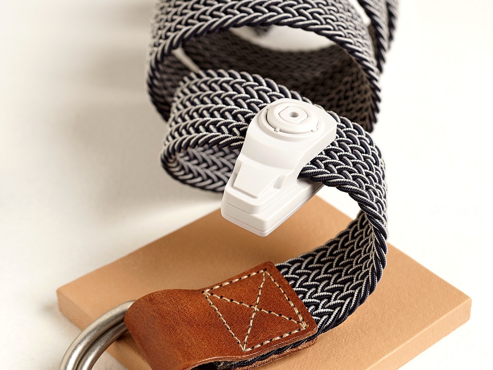 leather and braided fabric belt coiled and carrying an infuzion hard tag in retail accessories store
