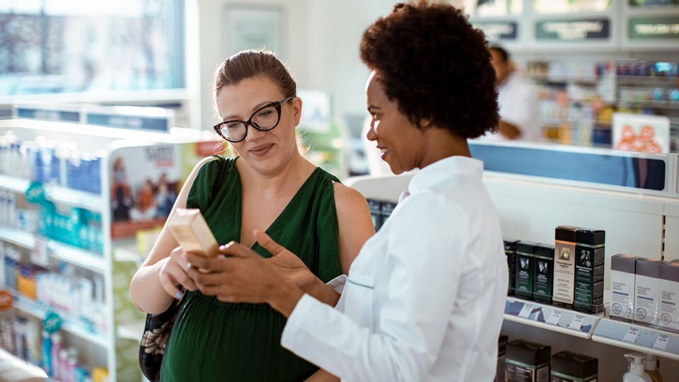 female pharmacist helps pregnant customer with deciding on a product in a retail pharmacy