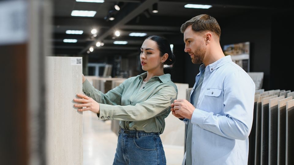 young male and female couple shopping in a retail hardware store for flooring look at samples on dissplay