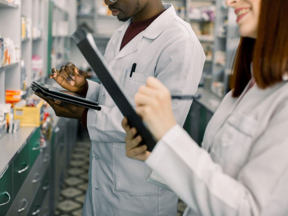 male and female retail pharmacy clerks checking merchandise inventory with electronic tablets