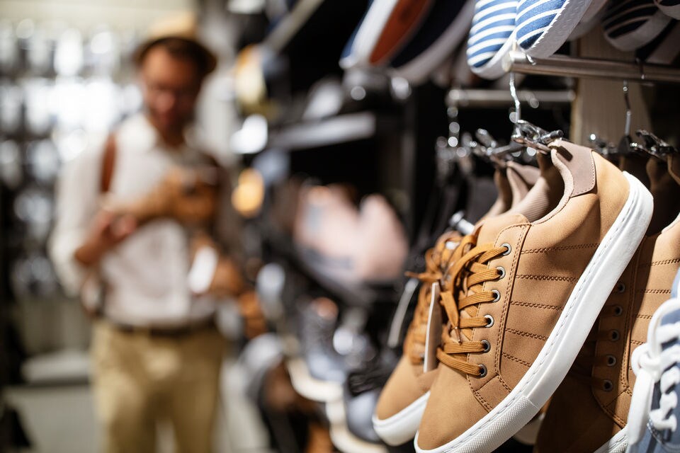 athletic shoes on wall display in retail footwear store with male customer in background