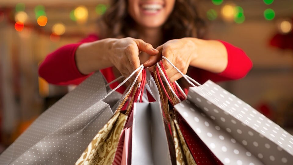 woman shopper holding multiple retail shopping bags after visiting many stores in the shopping mall at holiday season