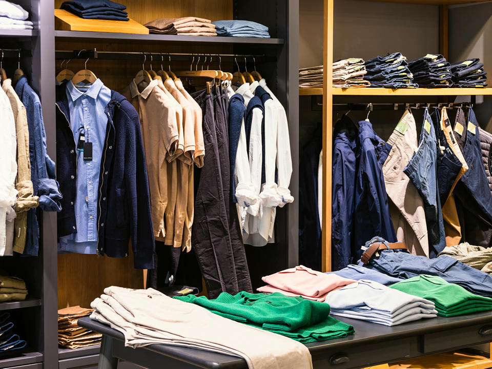 shirts and jeans displayed hanging on racks and folded on shelves in upscale mens retail apparel store