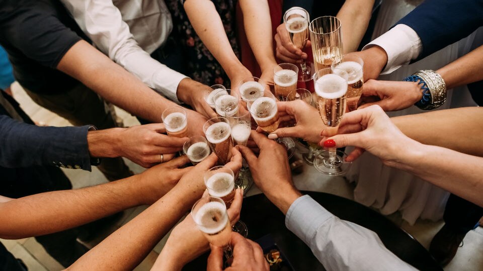 many hands holding champagne flute glasses making a toast