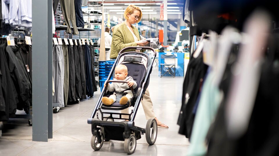 female shopper looking over items in retail department store while her child sits in stroller