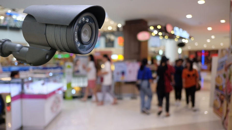 video surveillance camera in retail store with a group of shoppers blurred in the background