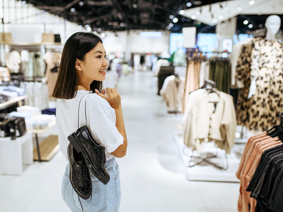 female shopper in apparel and accessories retail store carrying a pair of shoes to purchase