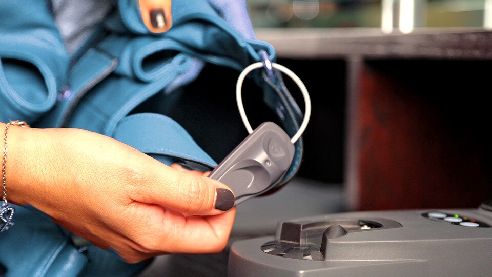 retail store employee associate removing sensormatic lanyard supertag from apparel using sensormatic tag detacher