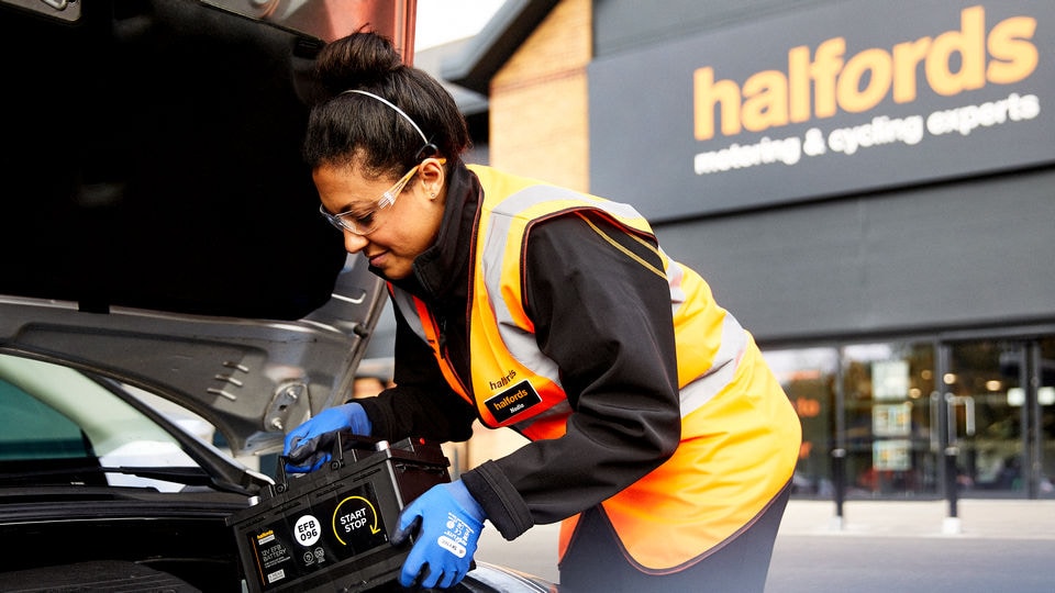 halfords automotive retail associate installing a battery in a customers car