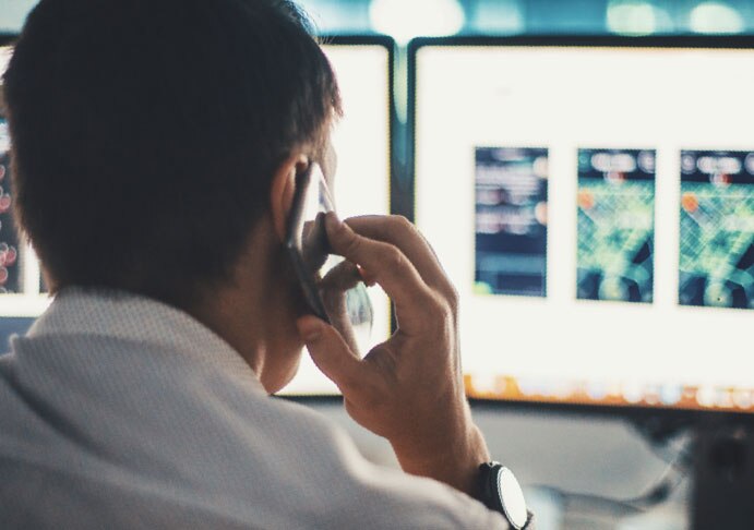 person on phone looking at computer screen