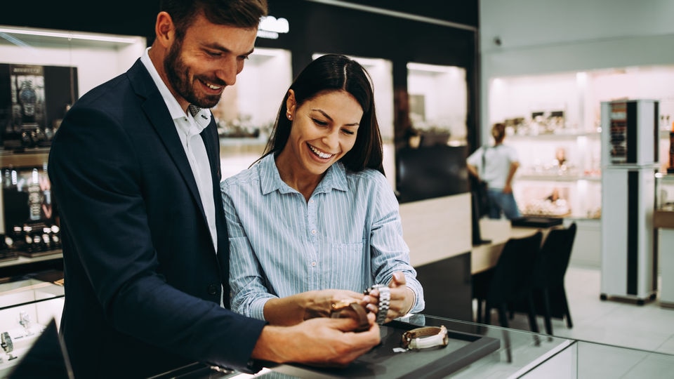 male and female customers in retail jewelry store looking over several wristwatches