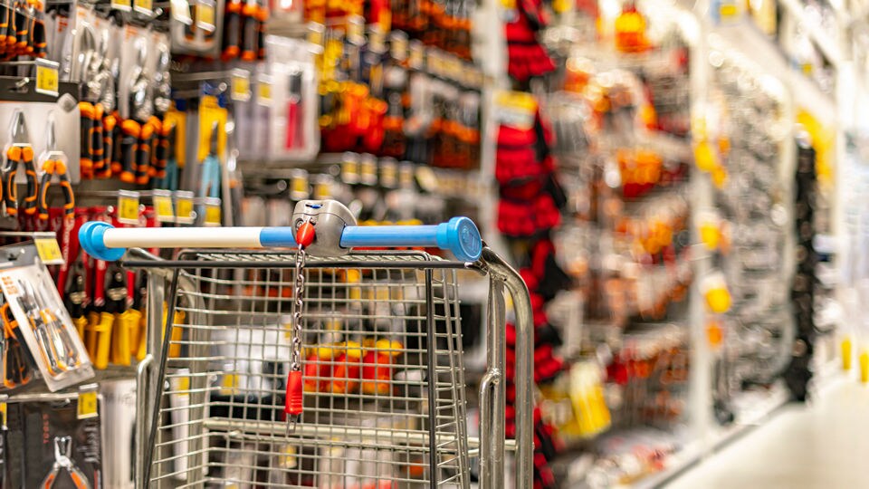 empty shopping cart with broken chain unattended in the tools aisle of a retail hardware store