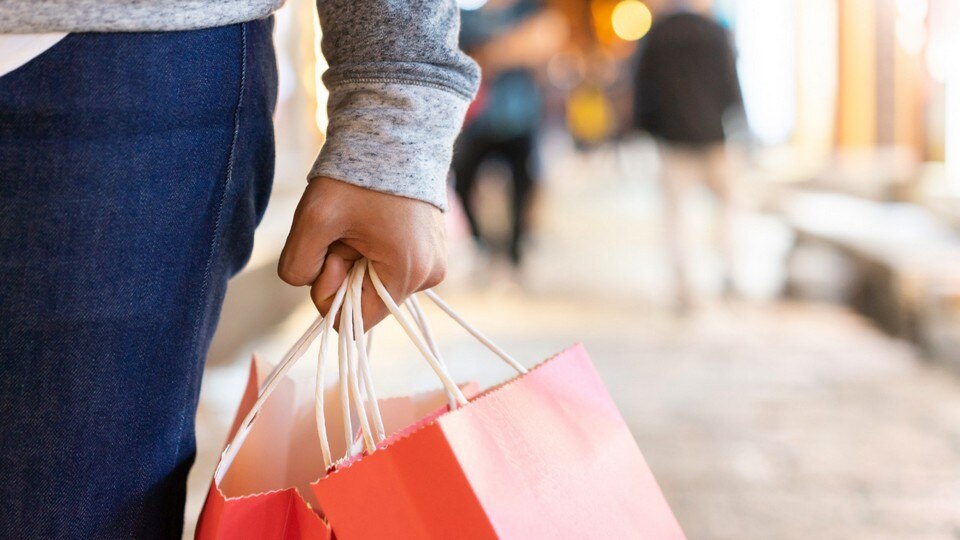 male retail shopper's hand carrying shopping bags