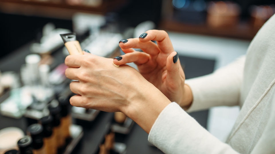 female shopper testing health and beauty product on her hand in retail store