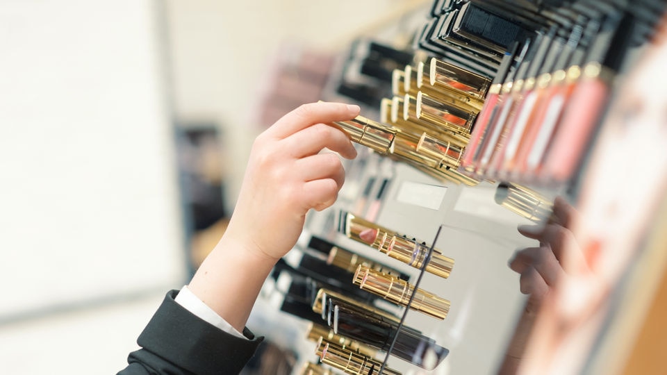 female hand choosing makeup item from retail health and beauty store display