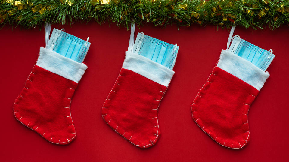 christmas stockings hanging on mantel with surgical mask in each