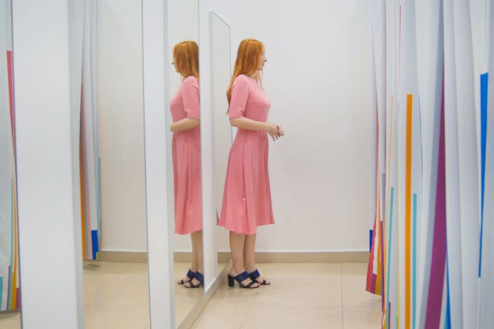 Mujer parcialmente reflejada en espejos de cuerpo entero en el probador