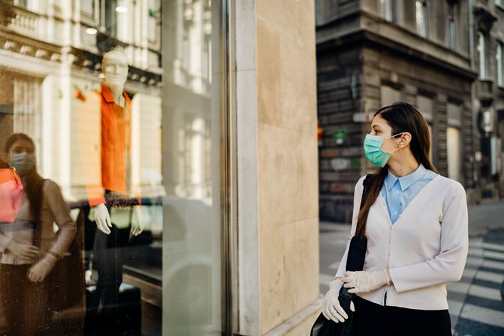 woman shopper in facemask looking into retail store window
