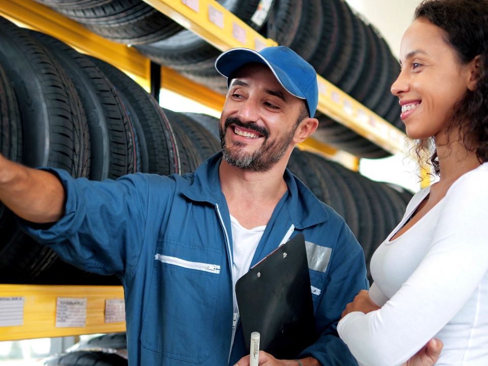 male retail automotive department employee helping a female shopper select tires for her car