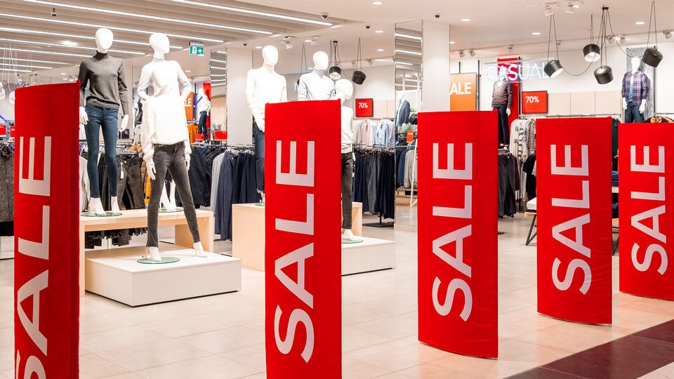 retail apparel store entrance with sale banners on loss prevention pedestals