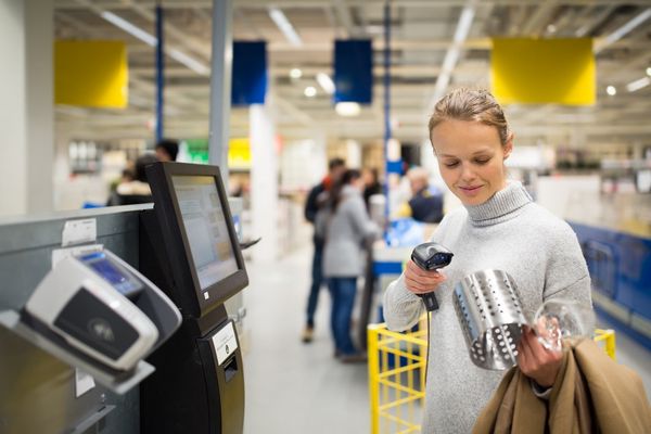 woman scanning item at retail store self-checkout