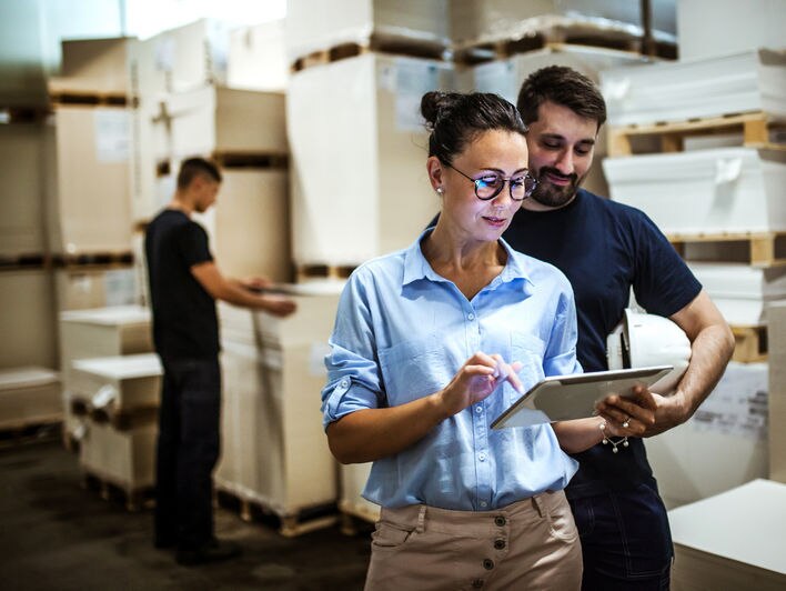 workers in retail warehouse conferring over mobile device