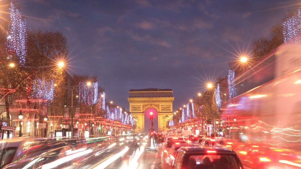 champs-élysées at sunset with traffic and festive lighting with the arc de triomphe in the distance