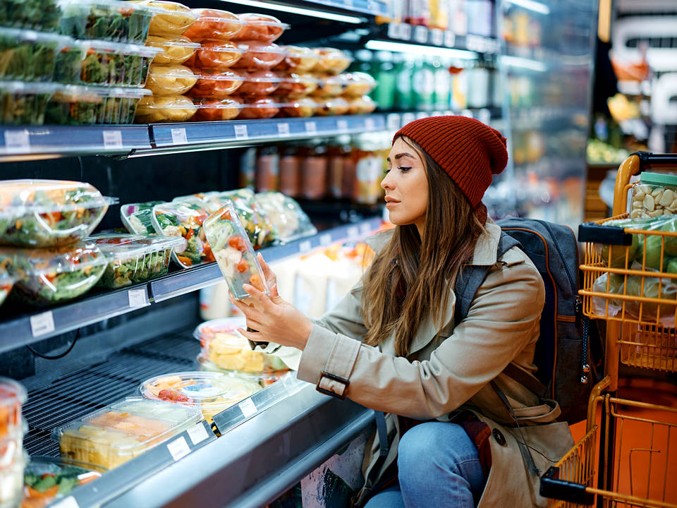 young woman shopper dressed warmly in refrigerated section of retail convenience store market