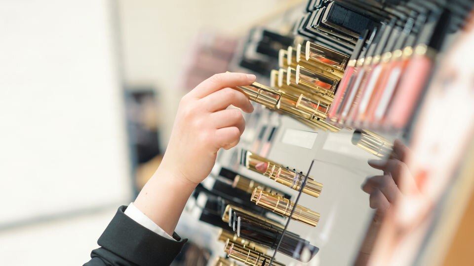 female hand choosing makeup item from retail health and beauty store display
