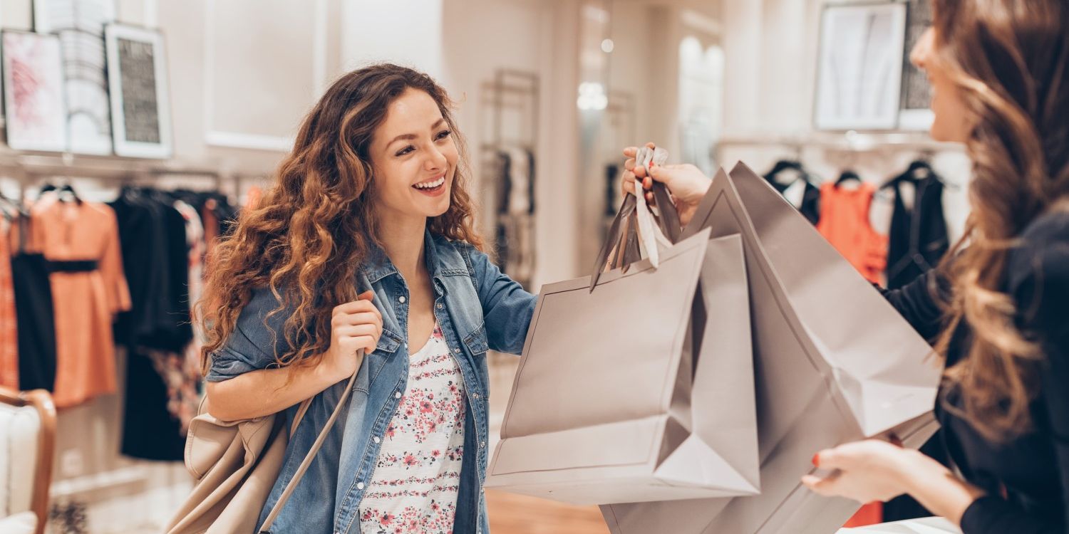 female customer taking shopping bags from store associate