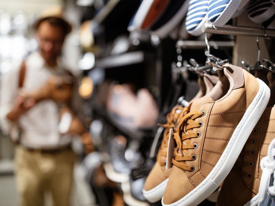 athletic shoes on wall display in retail footwear store with male customer in background
