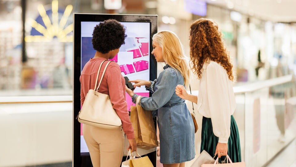 3 female shoppers in a retail shopping center looking at the mall directory map