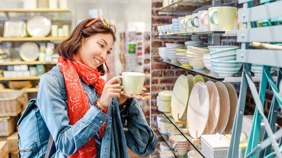 female shopper looking at cups and plates on a display in a retail store