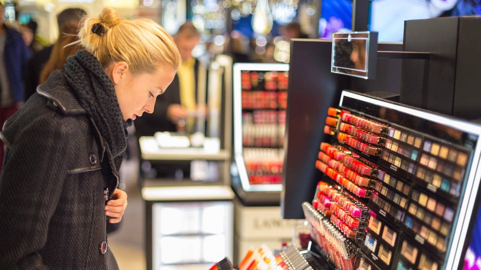 female shopper looking at display of makeup in a retail health and beauty store