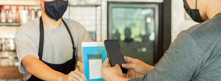 Male customer with protective mask paying bill by cell phone