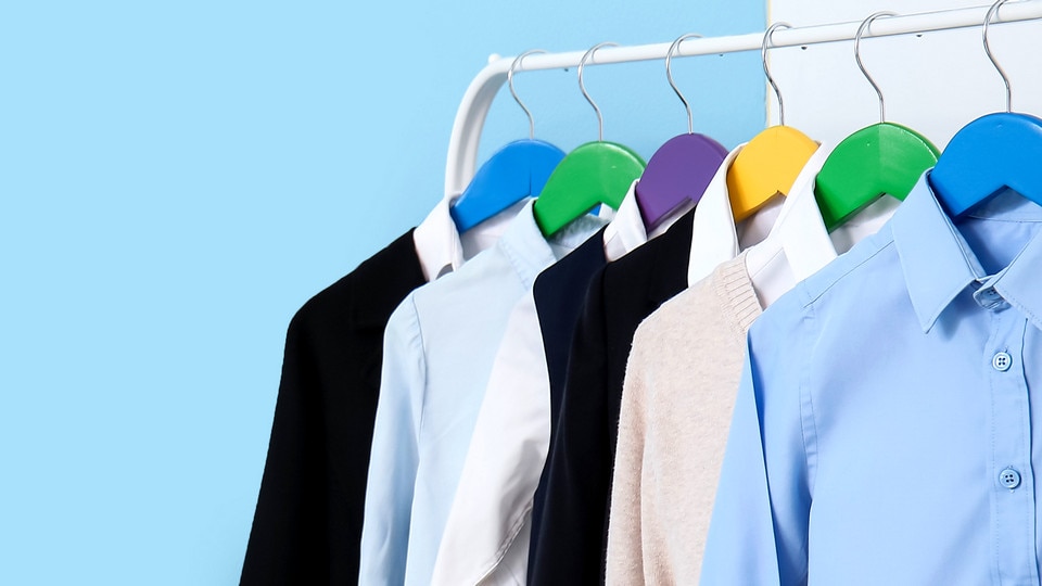 variety of uniform coats and shirts on hangers against a bright blue background